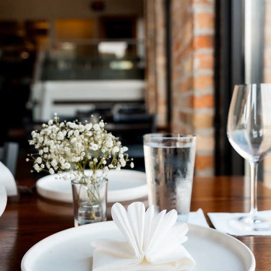 Reference image: Manufacturer lifestyle photo for Nature's Linen 40020 showing the napkin or guest towel in use. Supplied color: white. Decorative folds and display quantities are illustrative; this listing supplies the stated napkins or towels only. Food, beverages, glassware, plates, cutlery, furniture, plants and other props are not included. Dimensions, material, fold and case quantity are as listed above.